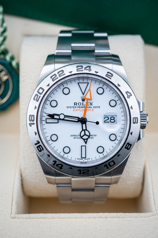 Silver Rolex watch with a white face on a beige cushion