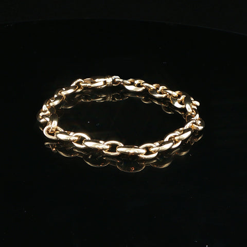 A gold chain link bracelet with a polished finish, displayed on a reflective black surface.