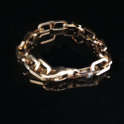 A chunky gold chain link bracelet with a lobster clasp, displayed on a reflective black surface.
