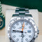 Silver Rolex watch with a white face on a beige cushion