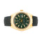 Gold watch with green face and black strap on a white background