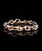 A rose gold chain link bracelet with a polished finish, displayed on a reflective black surface.