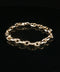 A gold chain link bracelet with a polished finish, displayed on a reflective black surface.