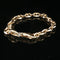 A gold-toned chunky chain bracelet with a lobster clasp, displayed on a reflective black surface.