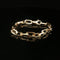 A gold chain link bracelet with a lobster clasp, displayed on a reflective black surface.