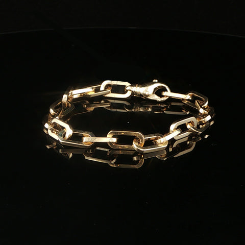 A gold chain link bracelet with a lobster clasp, displayed on a reflective black surface.